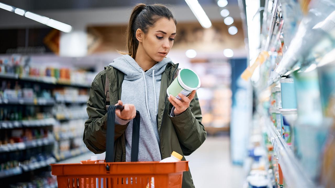 Woman reading label on food package at grocery store