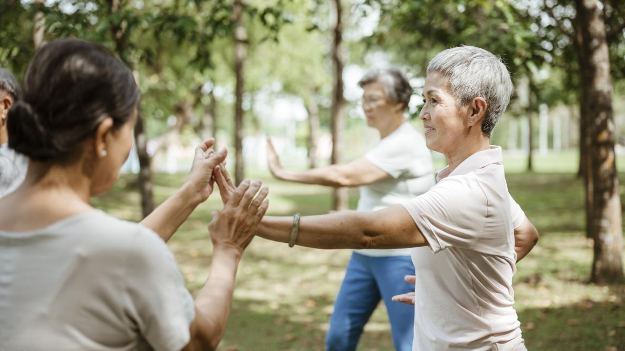 Group of people practicing movement exercises together in an outdoor setting.